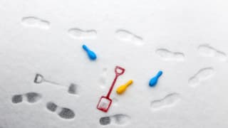 Eine rote Schaufel, zwei blaue und ein gelber Kegel im Schnee, rundherum Fussbadrücke.