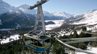 Eine Gondel an einem schönen Wintertag, im Hintergrund Blick ins Oberengadin.