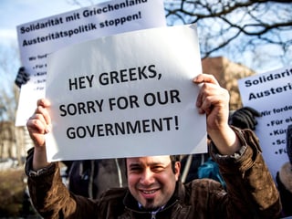 Ein Mann hält ein Plakat hoch: «Hey Greeks, sorry for our governement.»