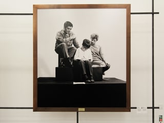 Eine Familie sitzt auf einem Sockel und ist Teil einer Ausstellung.