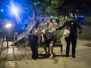 Ein Polizist hält einen jungen Mann am Arm, um ihn wegzuweisen. Neben dem Mann ist eine Frau. Ein Polizist hält einen jungen Mann am Arm, um ihn wegzuweisen. Neben dem Mann ist eine Frau.