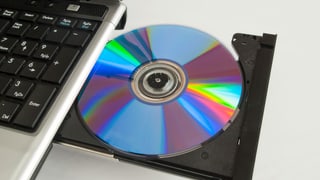 eine CD, die aus einem Laufwerk am Laptop kommt