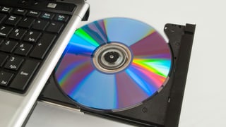 eine CD, die aus einem Laufwerk am Laptop kommt eine CD, die aus einem Laufwerk am Laptop kommt