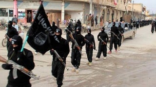 Schwarz gekleidete, vermummte und bewaffnete Dschihadisten defilieren auf einer Strasse. Schwarz gekleidete, vermummte und bewaffnete Dschihadisten defilieren auf einer Strasse.