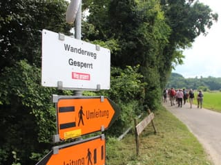 Ein Schild markiert den gesperrten Wanderweg, die Umleitungsschilder zeigen in zwei Richtungen.