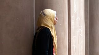 Eine Frau mit Hidschab steht vor einer Moschee. Eine Frau mit Hidschab steht vor einer Moschee.