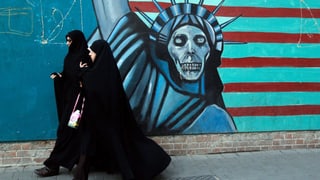 Frauen im Tschador in Teheran, dahinter die Freiheitsstatue als Skelett. 