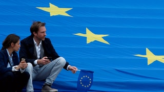 Menschen sitzen auf EU-Flagge.