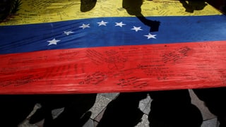 Eine venezolanische Flagge am Boden mit Kritzeleien darauf.