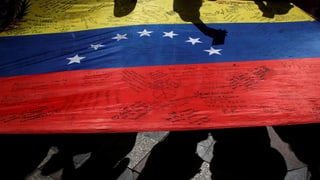 Eine venezolanische Flagge am Boden mit Kritzeleien darauf.