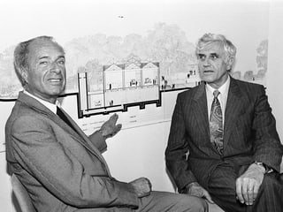 Archivbild: Zwei Männer im Anzug sitzen vor einer Bau-Skizze der Fondation.