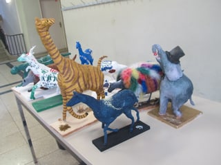 Tiere aus Papier maché aufgereiht auf einem Tisch im Schulhausgang.