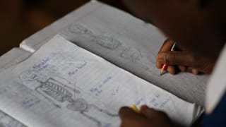 ein Kind schreibt in ein Schulbuch in seiner Muttersprache