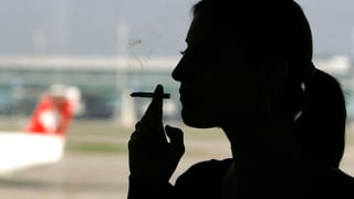 Symbolbild: Eine Frau raucht auf dem Flughafen im Gegenlicht.