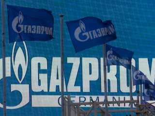 Flaggen vor einem Logo von Gazprom.