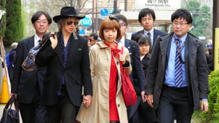Eine japanische Frau, umgeben von Männern in Anzug. Eine japanische Frau, umgeben von Männern in Anzug.
