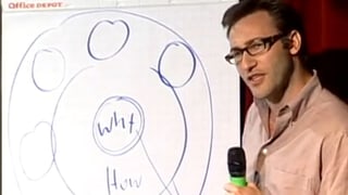 Ein Mann mit Brille und Mikrofon vor einer Skizze an einer Tafel.
