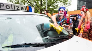 Clowns putzen die Frontscheibe eines Polizeiautos Clowns putzen die Frontscheibe eines Polizeiautos