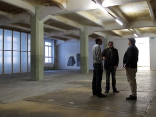 Drei Personen stehen in einem leeren Raum des Kulturzentrums Kammgarn.
