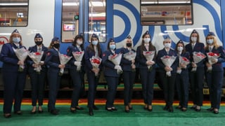 12 Frauen in Uniform stehen mit Rosensträussen in den Händen vor einem Zug. 12 Frauen in Uniform stehen mit Rosensträussen in den Händen vor einem Zug.