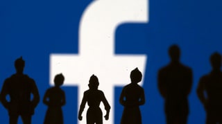 Silhouetten von Menschen vor einen grossen Facebook-Logo.