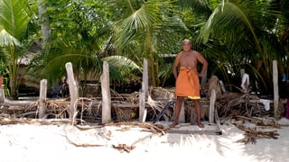 Ein Mann steht vor einem Palmenzaun.