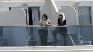 Zwei Frauen mit Gesichtmasken auf Balkon eines Schiffes.