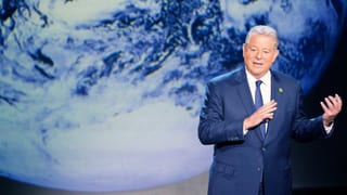 Al Gore steht vor einer riesigen Projektion der Erde.