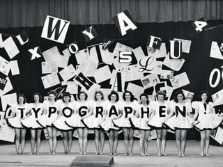 12 Ballettänzerinnen posieren auf der Bühne mit je einem Buchstaben auf dem Kleid. Es ergibt sich das Wort «Typographen» mit Ausrufezeichen.