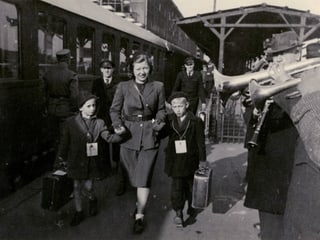 Eine Frau läuft auf dem Bahnsteig mit zwei Kinder links und rechts von ihr an der Hand. 