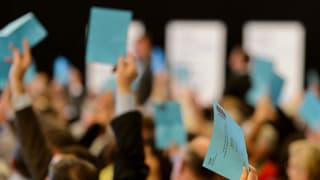 Delegierte der FDP stimmen mit ihrer weissen Einladung ab, die sie hochstrecken.