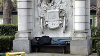Mann ohne zu Hause schläft auf einer Bank.