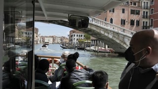 Menschen mit Masken auf einem Schiff in Venedig
