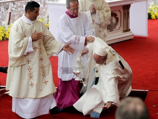 Papst Franziskus stolpert und wird aufgefangen.