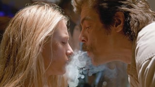 Ein Mann bläst einer Frau Rauch ins Gesicht.