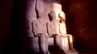 In Stein geschlagene Pharaofiguren werden von spärlichem Sonnenlicht beleuchtet