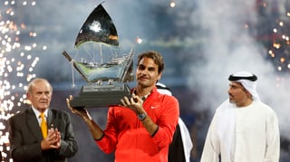 Roger Federer hält eine Trophäe in die Höhe.