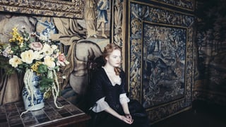 Emma Stone sitzt als Kammerzofe Abigail auf einem Stuhl im Palast.