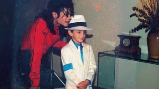 Michael Jackson steht hinter einem kleinen Jungen, hält ihn an der Schulter und posiert für ein Foto.