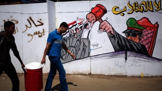 Zwei junge Männer gehen an einer Wand vorbei, darauf ein Grafitti: Mursi-Anhänger wehren sich gegen den Militärchef.