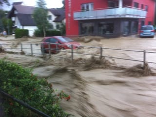 Ein Auto fährt auf einer überfluteten Strasse