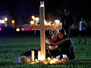 Trauernde Leute vor Kreuz.