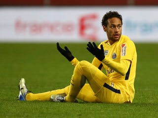 Neymar sitzt auf dem Spielfeld und beklagt sich.