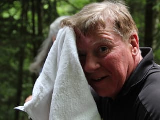 Ein Wanderer tupft sich mit einem Frottiertuch den Schweiss von der Stirn.