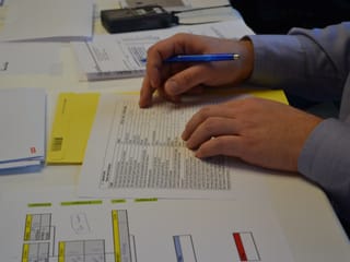 Blick auf das Blatt Papier mit dem Fragekatalog.