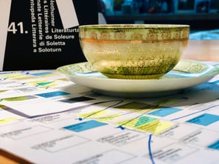 Eine Tasse Grüntee steht auf Audrucken mit dem Programm der Solothurner Literaturtage Eine Tasse Grüntee steht auf Audrucken mit dem Programm der Solothurner Literaturtage