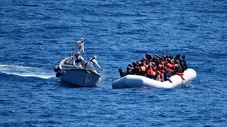 Ein Schiff der italienischen Marine nähert sich einem Schlauchboot. 
