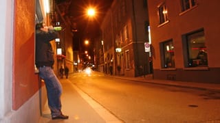 Ein Mann trinkt in einer städtischen Gasse aus einer Flasche Bier. Ein Mann trinkt in einer städtischen Gasse aus einer Flasche Bier.