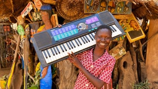 ein schwarzes Mädchen hält ein Keyboard in der Hand
