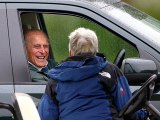 Prinz Philip sitzt in seinem stehenden Auto am Steuer und spricht über die heruntergelassene Fensterscheibe zu einem Passanten.